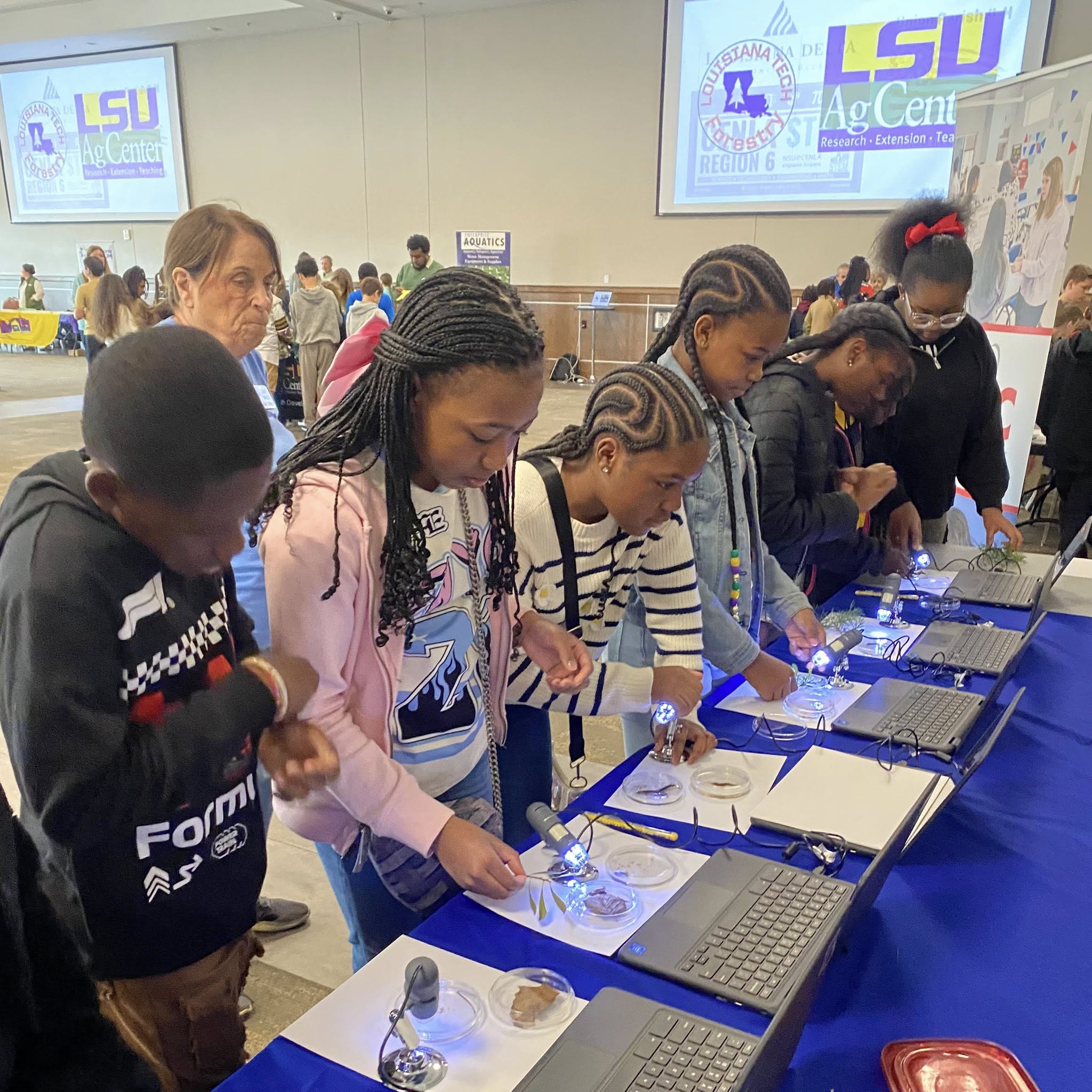 A group of kids lined up at a table with papers and small lights in front of them.